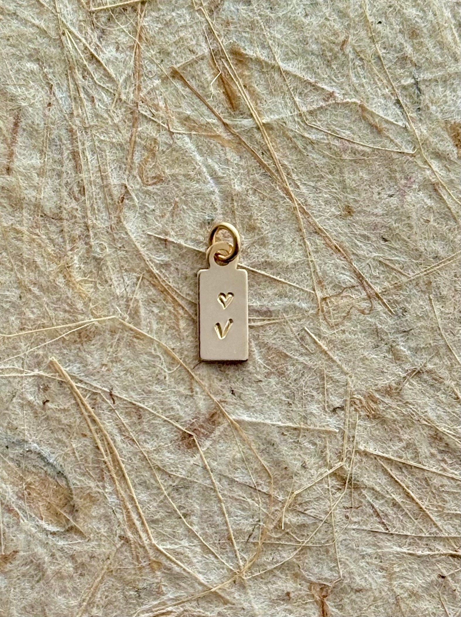 Mini Tag Initial Charm shot as a close up to see details of the mini tag charm