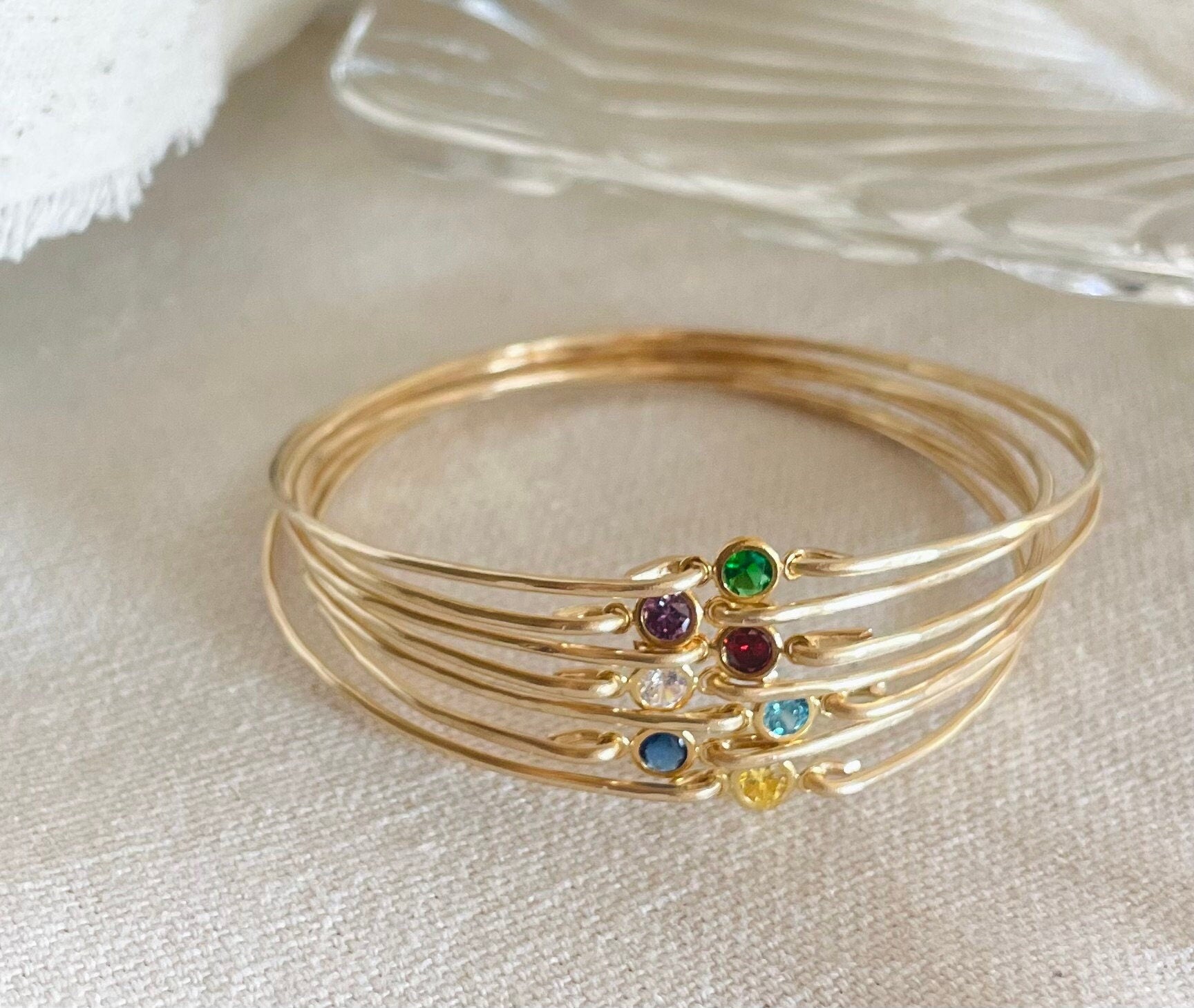 Dainty birthstone bangle featuring sparkling CZ diamonds, ideal for stacking and layering, perfect for brides, bridesmaids, and gifts. Bangles on Fabric.